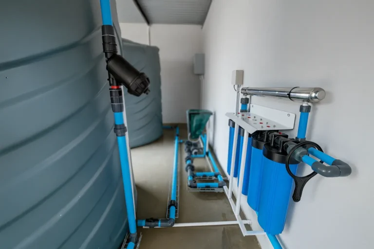 Indoor borehole water filtration system with pre-filters, pressure vessels, and blue piping.